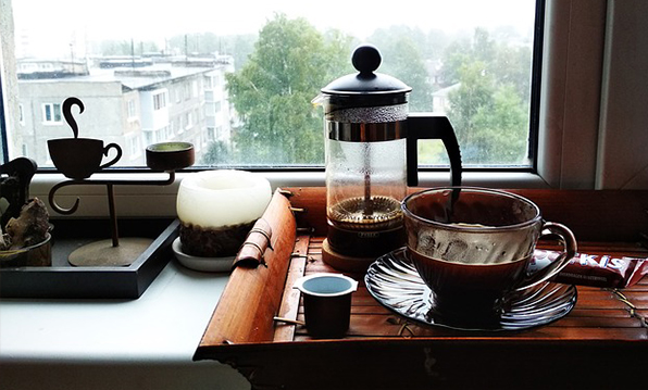 French press and a cup of coffee on a window sill