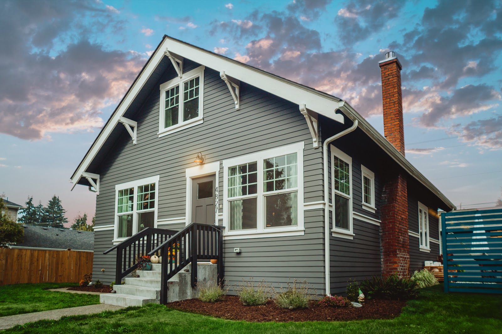 Grey sided home with large windows in evening light