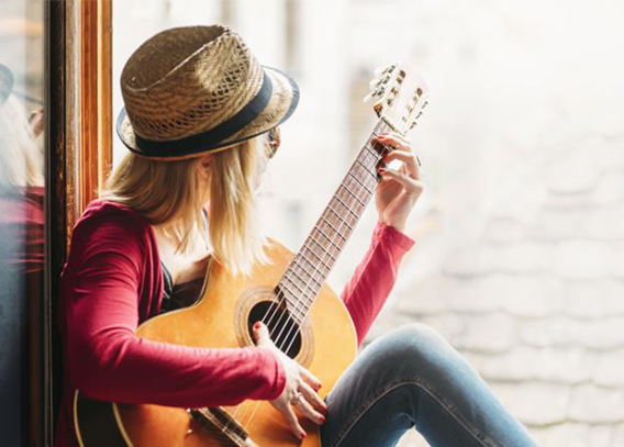 A person enjoying sunlight while playing the guitar