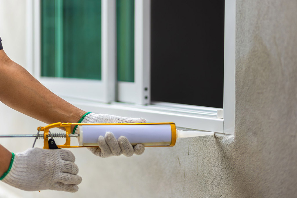 A person applying caulk on window edges