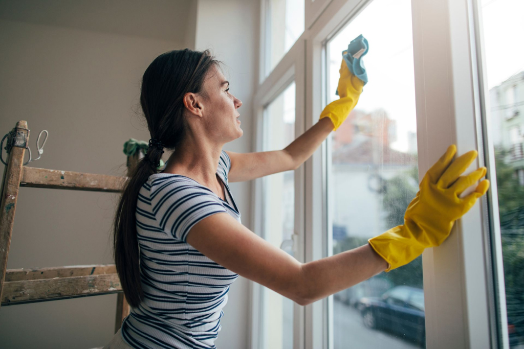A woman cleaning the window glass interior with a microfibre cloth 